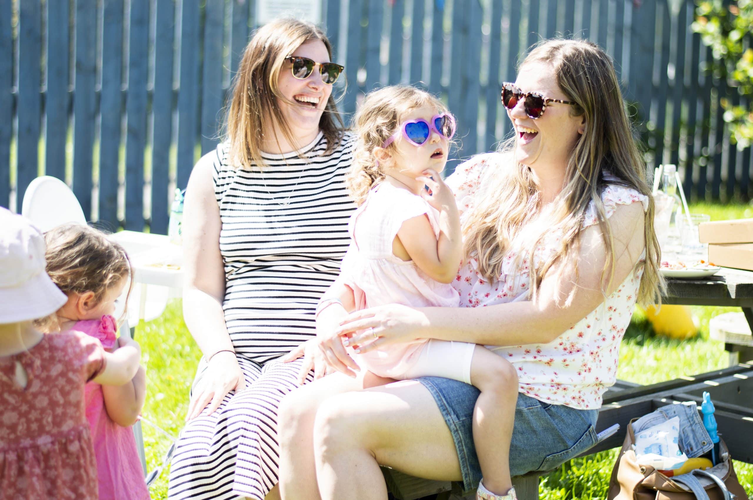 Two mums with toddlers laughing and chatting in the Coffee Shop garden